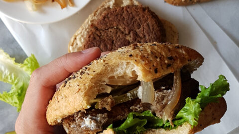 Burger végétarien vu de haut dans une main avec une bouchée prise