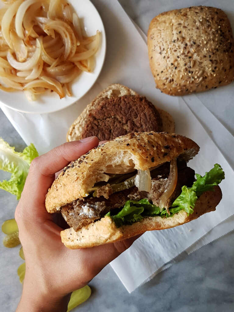 Burger végétarien vu de haut dans une main avec une bouchée prise