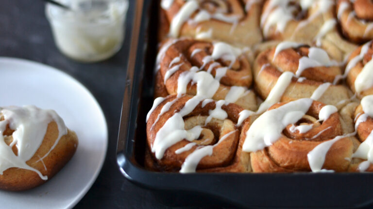 Brioches à la cannelle dans un plat de cuisson avec garniture au fromage à la crème