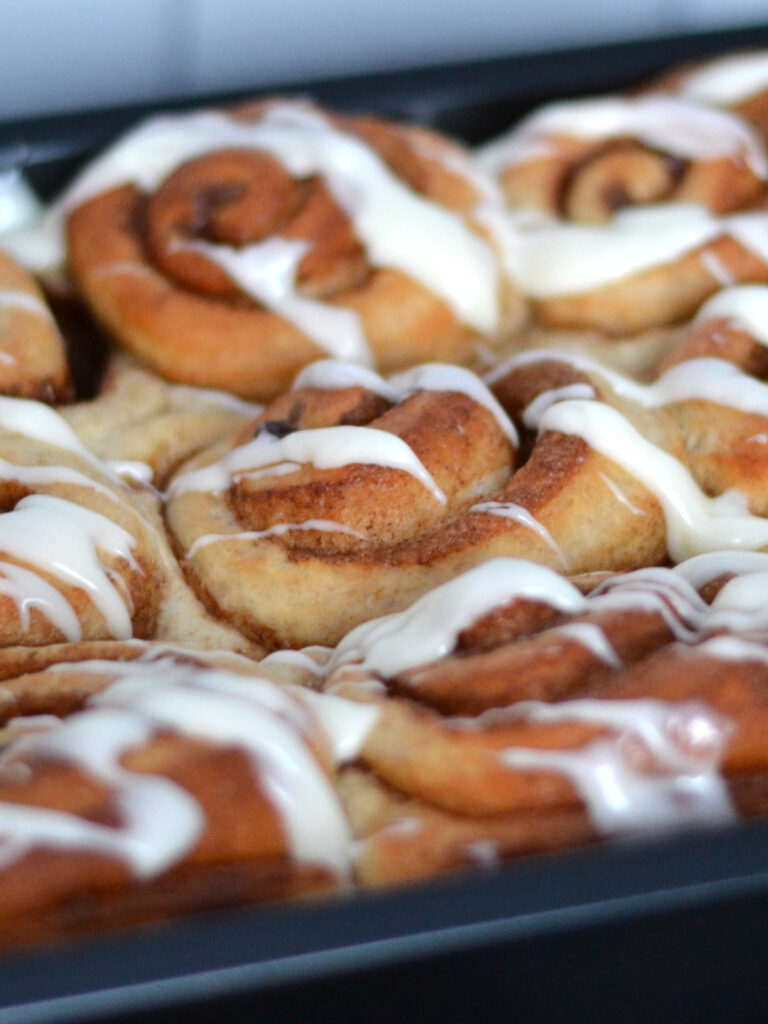 Brioches à la cannelle dans un plat de cuisson avec garniture au fromage à la crème