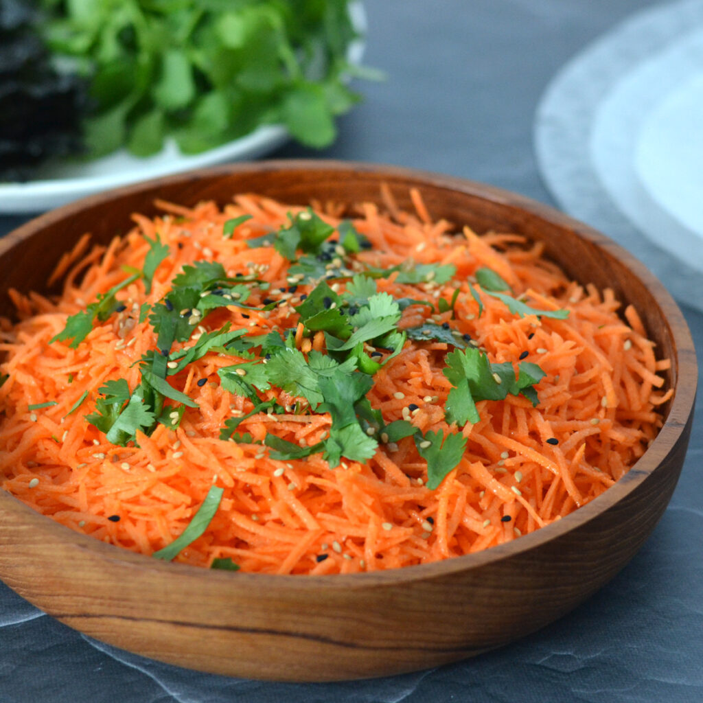 Salade de carottes et sésame Salade de carottes râpées garnie de sésame et de coriandre fraiche dans un bol de bois