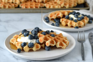 Gaufres avoine dans une assiette garnies de yogourt grec, bleuets et sirop d'érable coulant