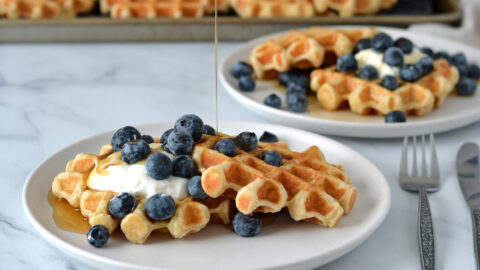 Gaufres avoine dans une assiette garnies de yogourt grec, bleuets et sirop d'érable coulant