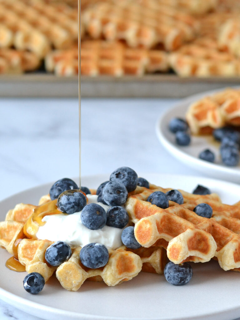 Gaufres avoine dans une assiette garnies de yogourt grec, bleuets et sirop d'érable coulant