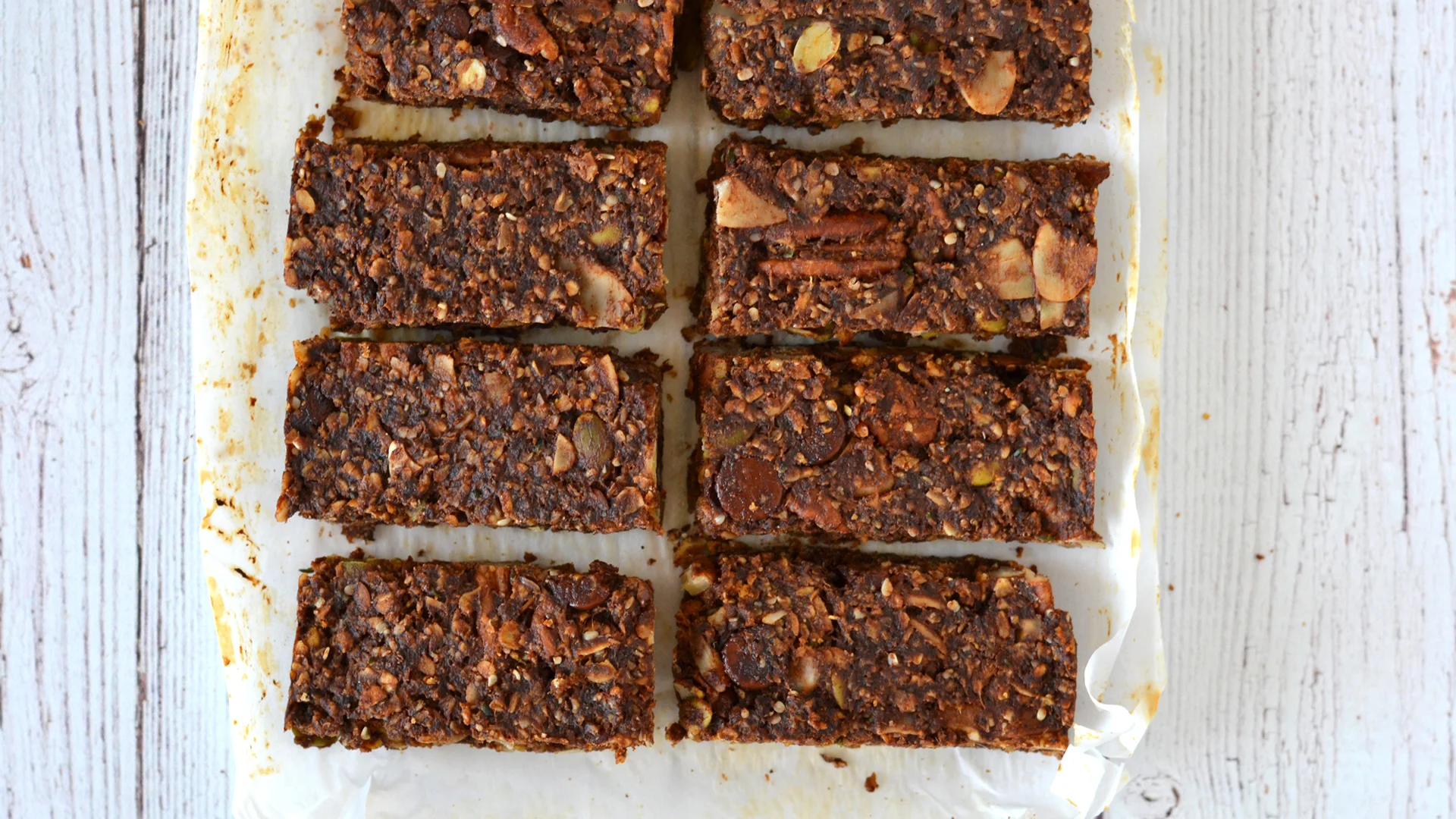 Barres énergétiques chocolatées aux dattes sur un papier parchemin, vu de haut.