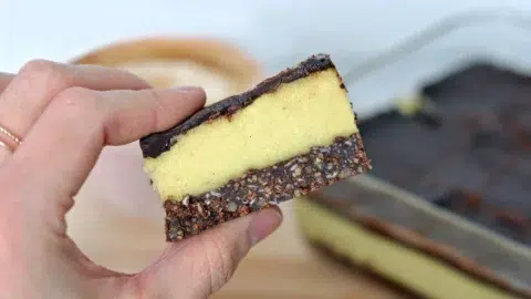 Plan rapproché d'une barre protéinée nanaimo tenu entre deux doigts.