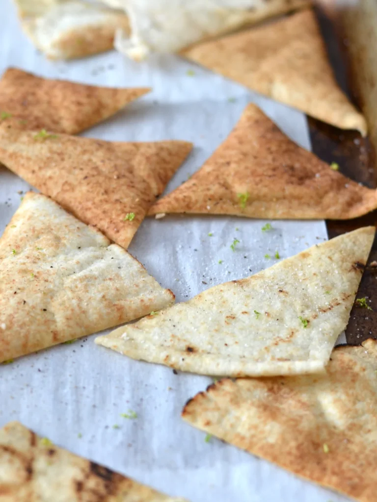 Chips de pain pita cuite au four, sur une plaque, garnies de poivre et de zeste de lime