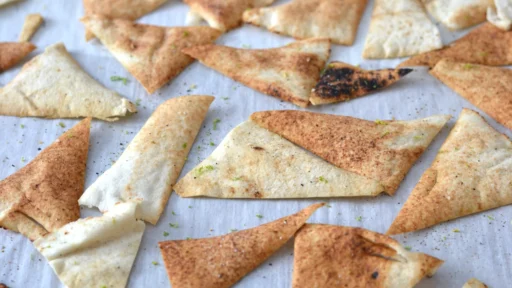 Chips de pain pita cuite au four, sur une plaque, garnies de poivre et de zeste de lime