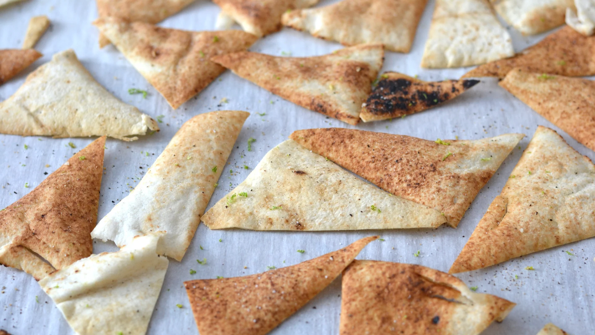 Chips de pain pita cuite au four, sur une plaque, garnies de poivre et de zeste de lime