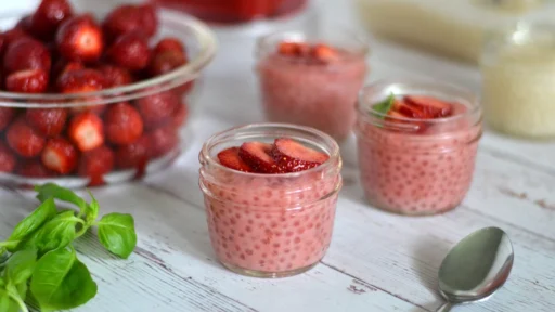 Tapioca au lait de coco et aux fraises Pouding de tapioca lait de coco et fraises servi dans trois pots Masson avec des feuilles de basilic.